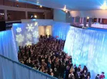 Crowded party with winter-themed decorations and blue lighting.