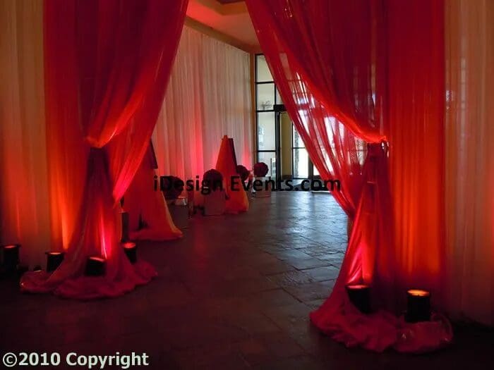 Elegant event space with red drapes and ambient lighting.