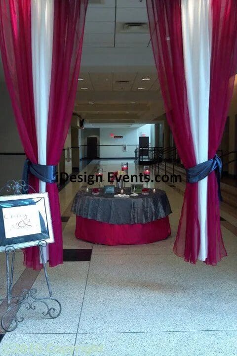 Elegant event entrance with deep pink and white drapes framing a decorated table.