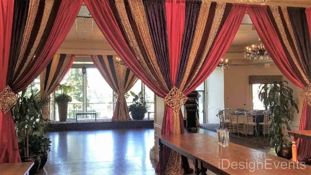 Elegant draped curtains in warm colors with a central tieback in a spacious room.