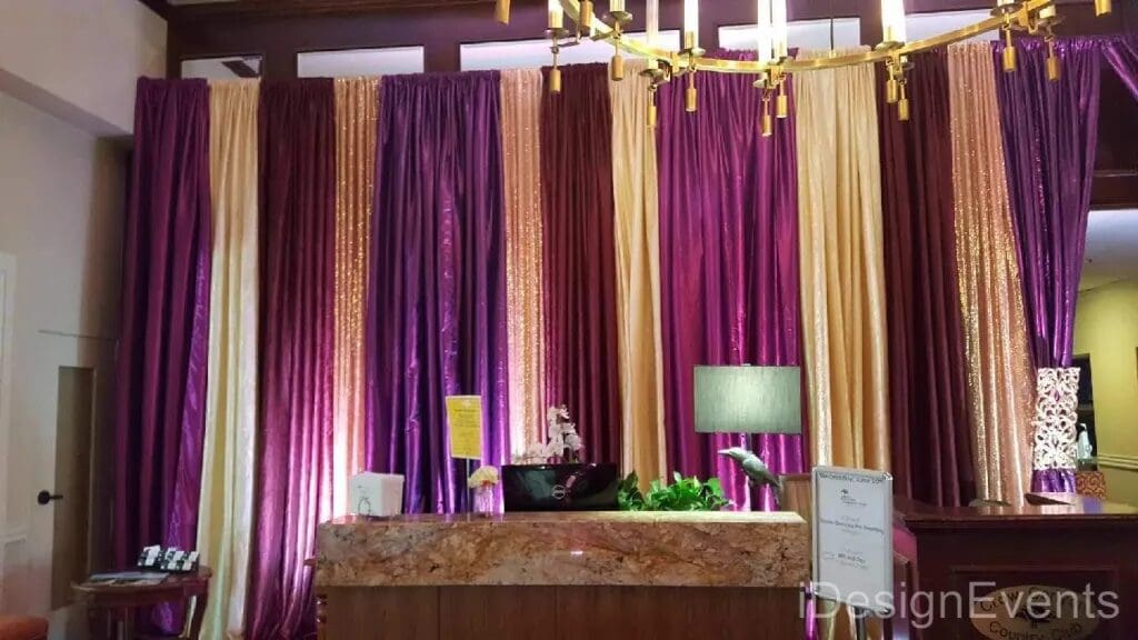 Decorative curtain backdrop with purple and gold tones behind a reception desk.