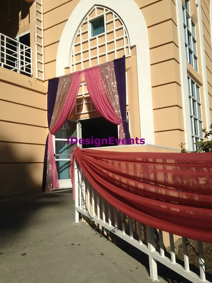 Wedding venue decorated with maroon and purple drapes and fairy lights.