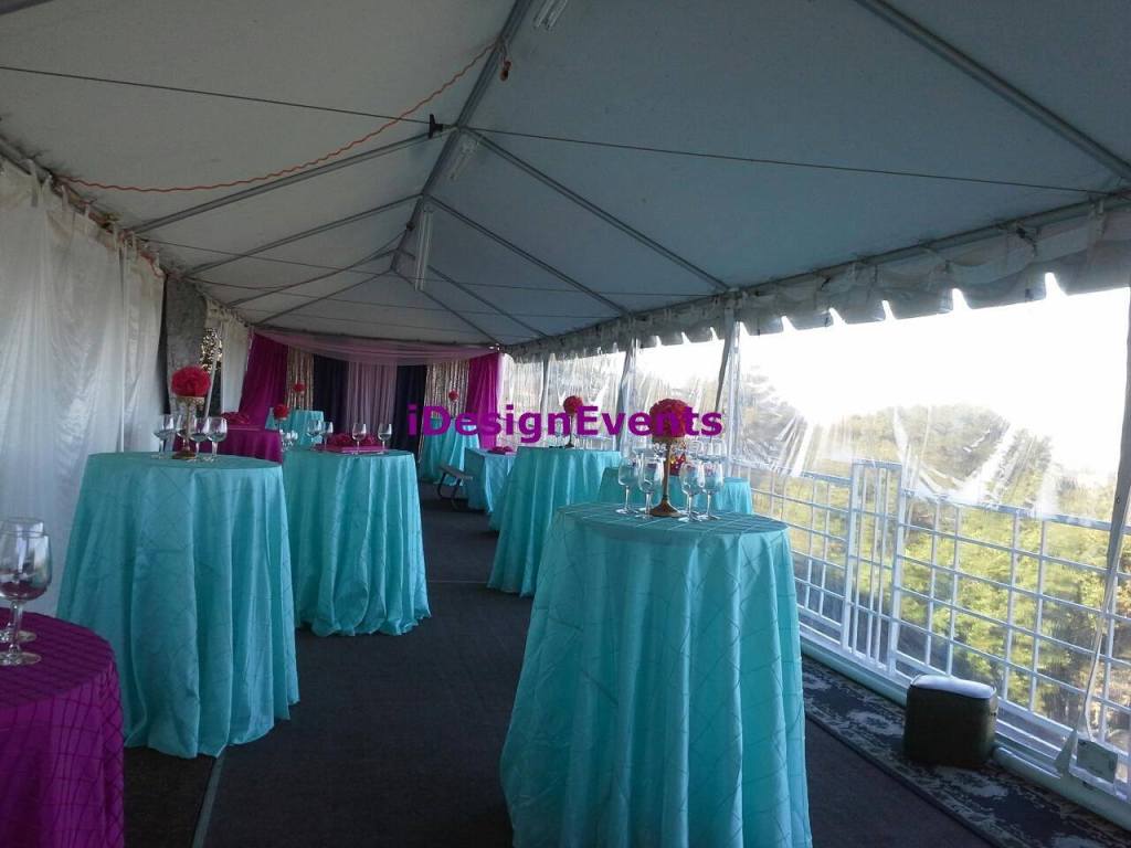 Elegant outdoor event setup with turquoise tablecloths under a white canopy.