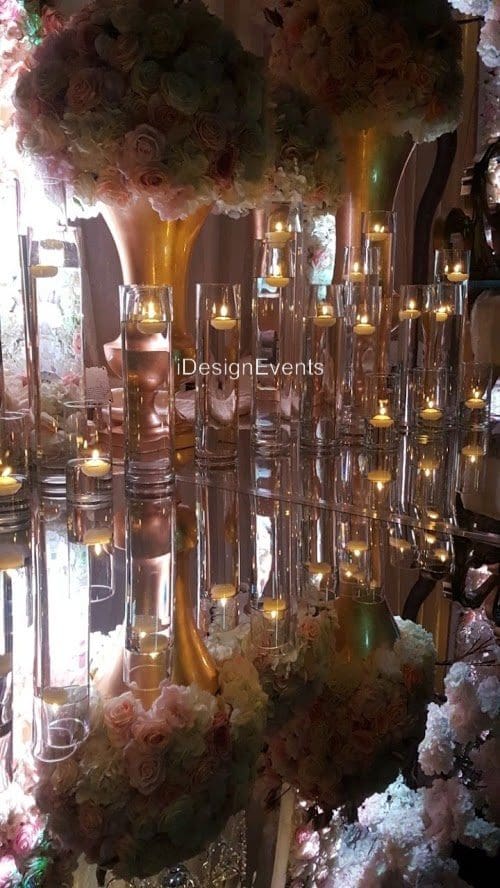 Elegant glass candle holders with lit candles reflecting on a glossy surface.