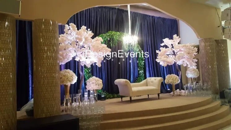 Elegant stage setup with white floral arrangements and a cream sofa.