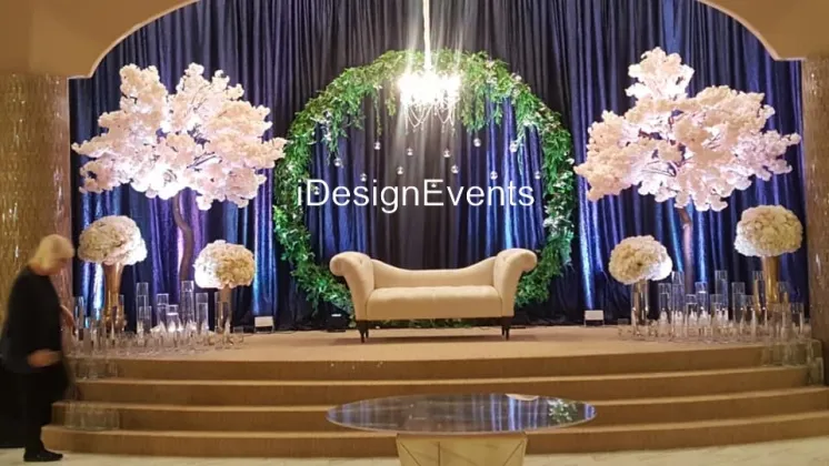 Elegant wedding stage with floral arrangements and a luxurious sofa.