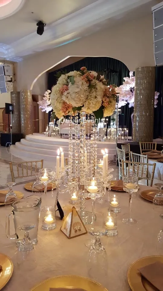 Elegant wedding table centerpiece with flowers and hanging crystals.