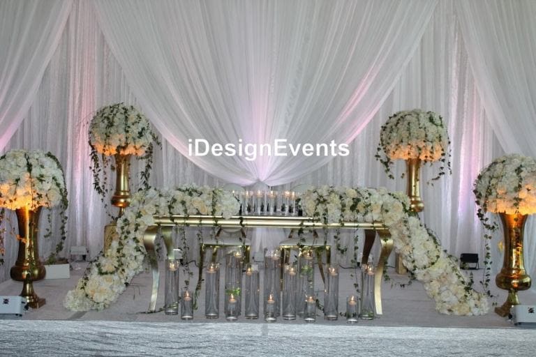Elegant wedding stage decorated with white flowers and draped fabric.