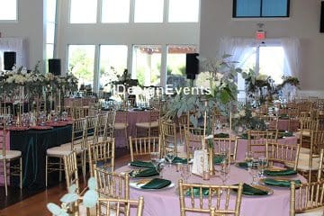 Elegant event setup with gold chairs and natural floral centerpieces.