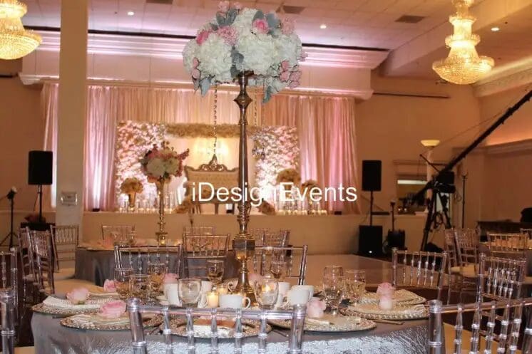 Elegant wedding table centerpiece with tall floral arrangement and candles.