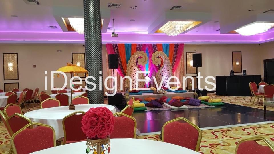 Colorful event setup with vibrant drapes and floral centerpieces.