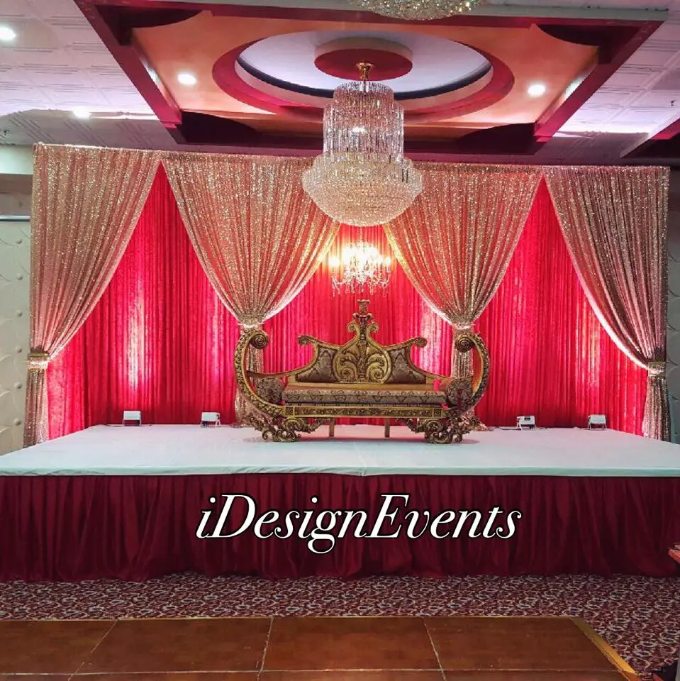 Elegant wedding stage with red curtains and crystal chandelier.
