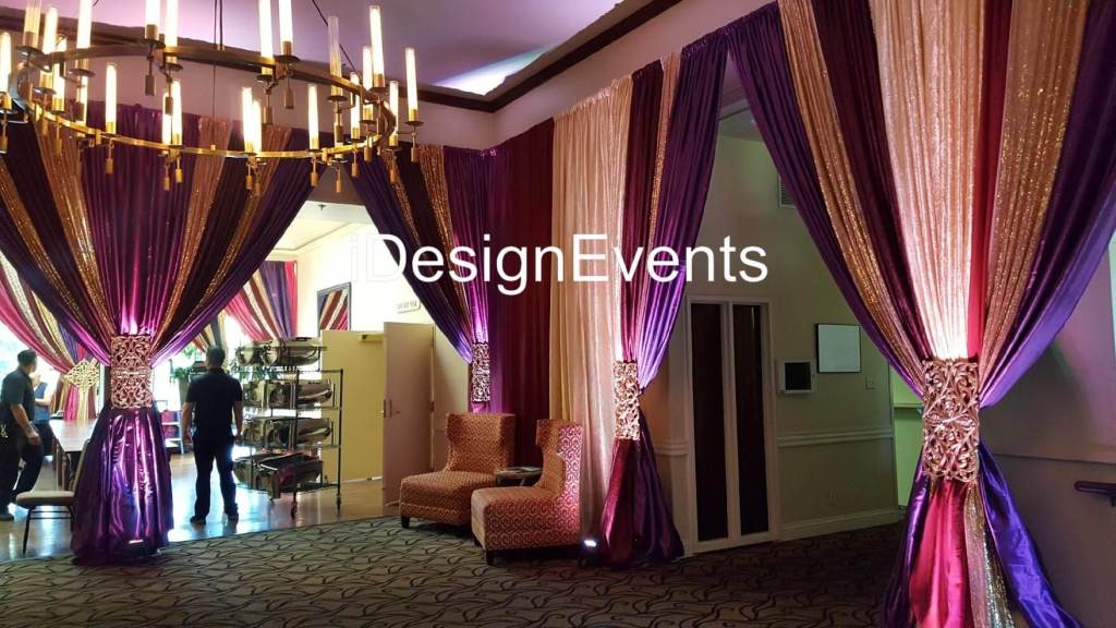 Elegant event space with luxurious purple curtains and warm lighting.