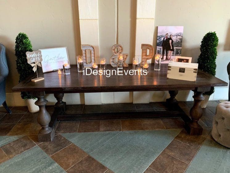 Elegant wooden table with decorative items and framed photos at an event.