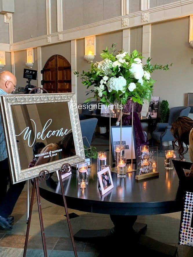 Elegant wedding welcome table with flowers, candles, and framed photos.