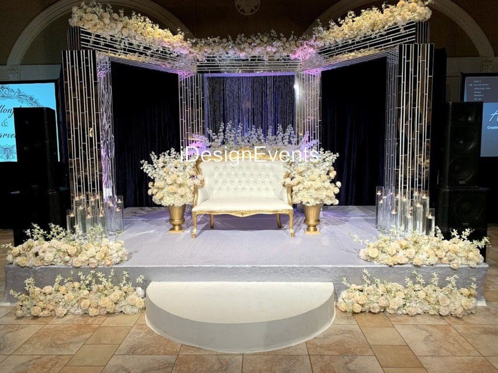 Elegant white and gold wedding stage with floral decorations.