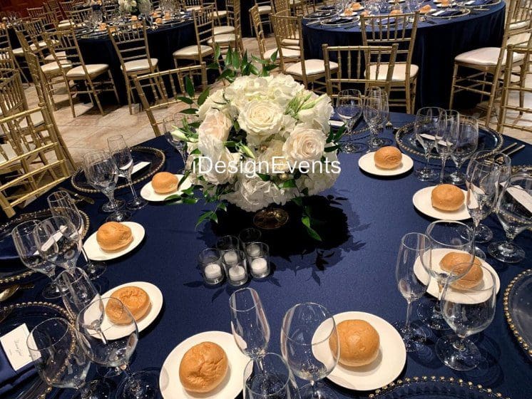 Elegant table setting with navy tablecloth and floral centerpiece.