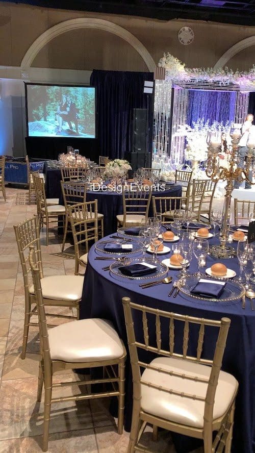 Elegant banquet setup with navy tablecloths and gold chairs.