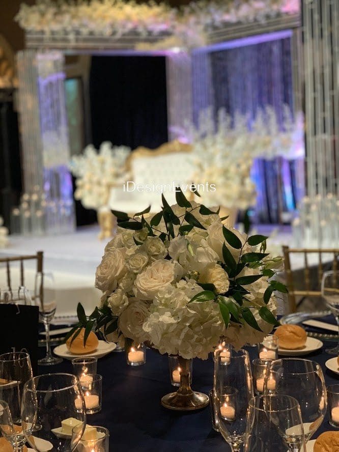 Elegant white floral centerpiece at a formal event with ambient lighting.