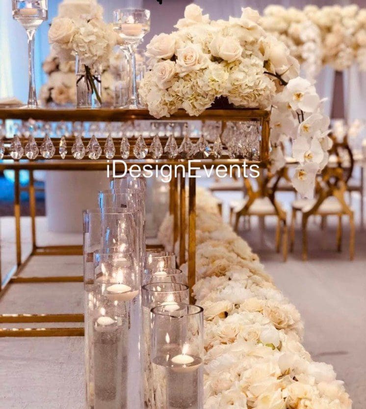 Elegant wedding aisle decorated with white flowers and candles in glass holders.