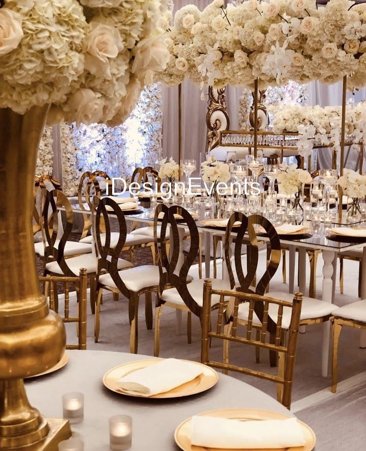 Elegant wedding reception setup with gold chairs and floral decorations.