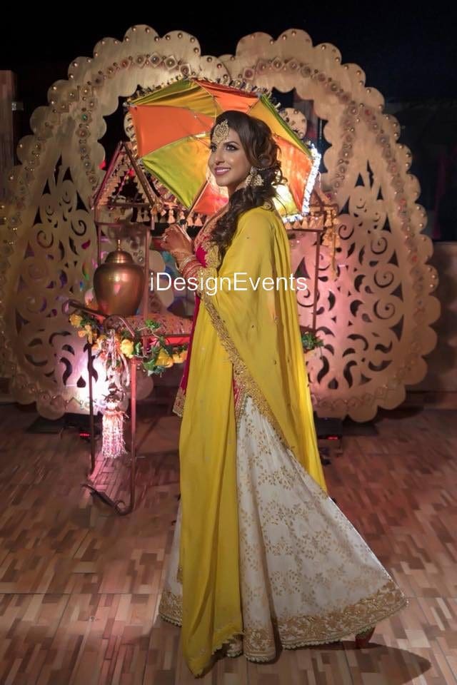 Woman in a vibrant yellow traditional outfit holding a decorative umbrella.