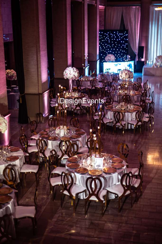 Elegant event setup with beautifully decorated round tables and warm lighting.