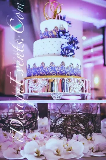 Elegant three-tier wedding cake with purple floral decor and gold accents.
