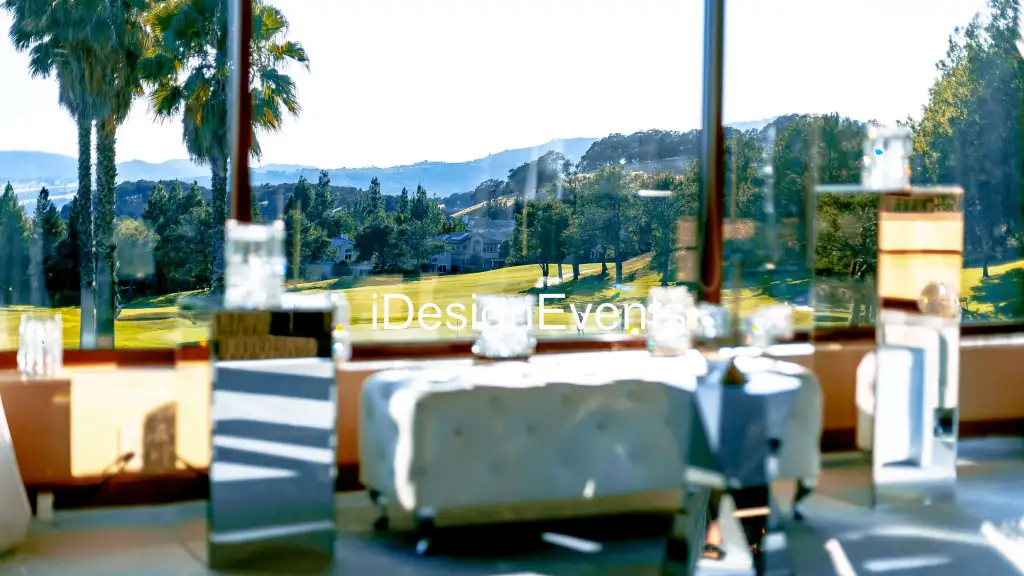 Sunny outdoor lounge area with white cushioned seats and a scenic hilly backdrop.