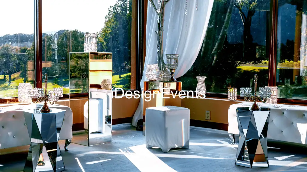 Elegant event setup with mirrored pedestals and white chairs under a tent.