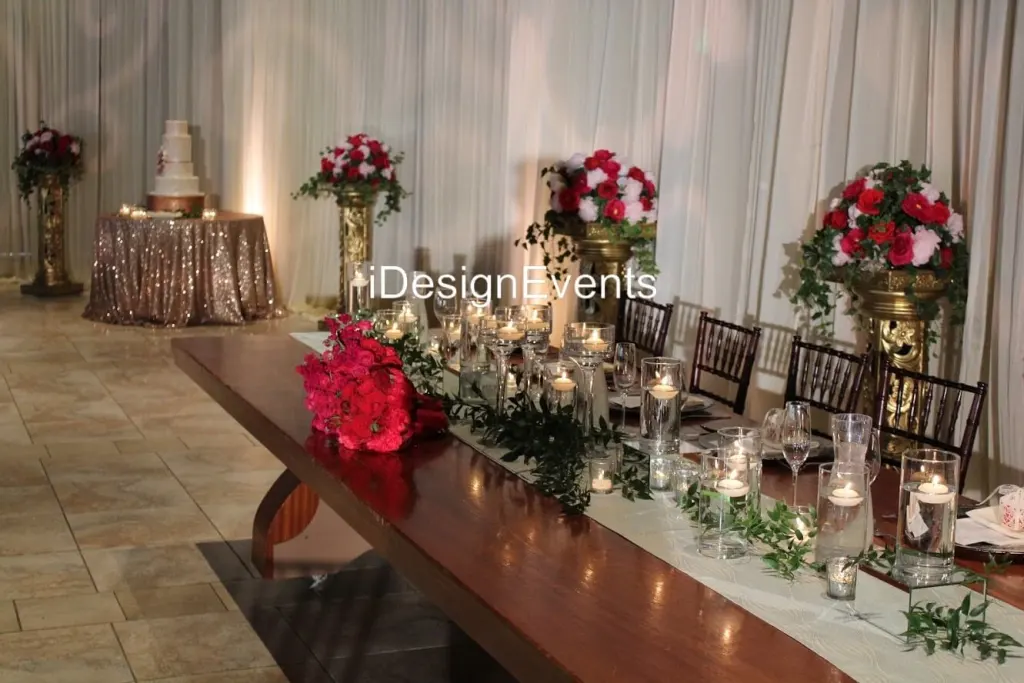 Elegant table setup with candles and pink flower centerpiece in a softly lit room.