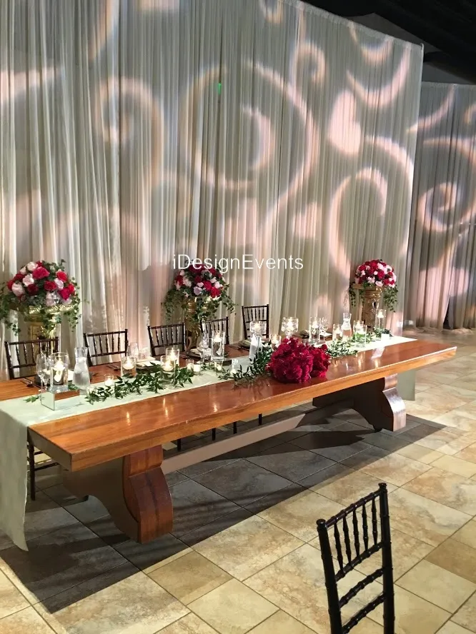 Elegant wedding table with roses and candles on a wooden bench.