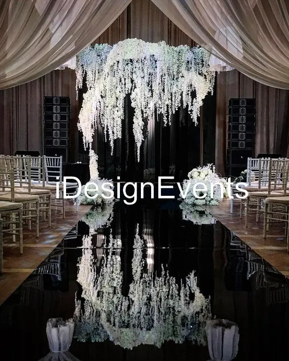 Elegant wedding aisle with cascading white flowers and reflective black floor.