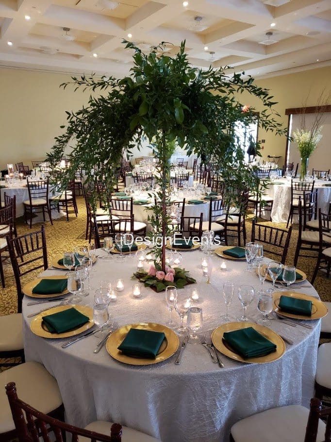 Elegant banquet table with greenery centerpiece and neatly arranged tableware.