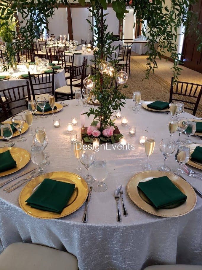 Elegant wedding table setting with green napkins and floral centerpiece.
