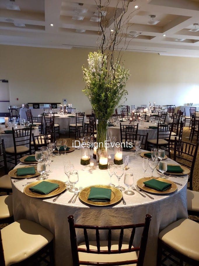Elegant banquet tables set with green napkins and floral centerpieces for an event.