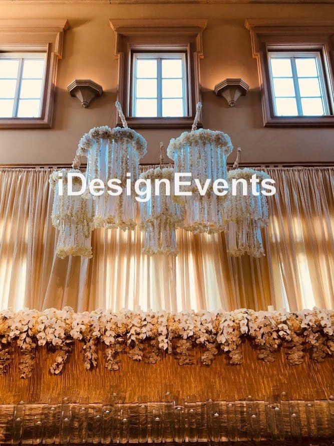 Elegant venue with chandeliers and floral decor under warm lighting.