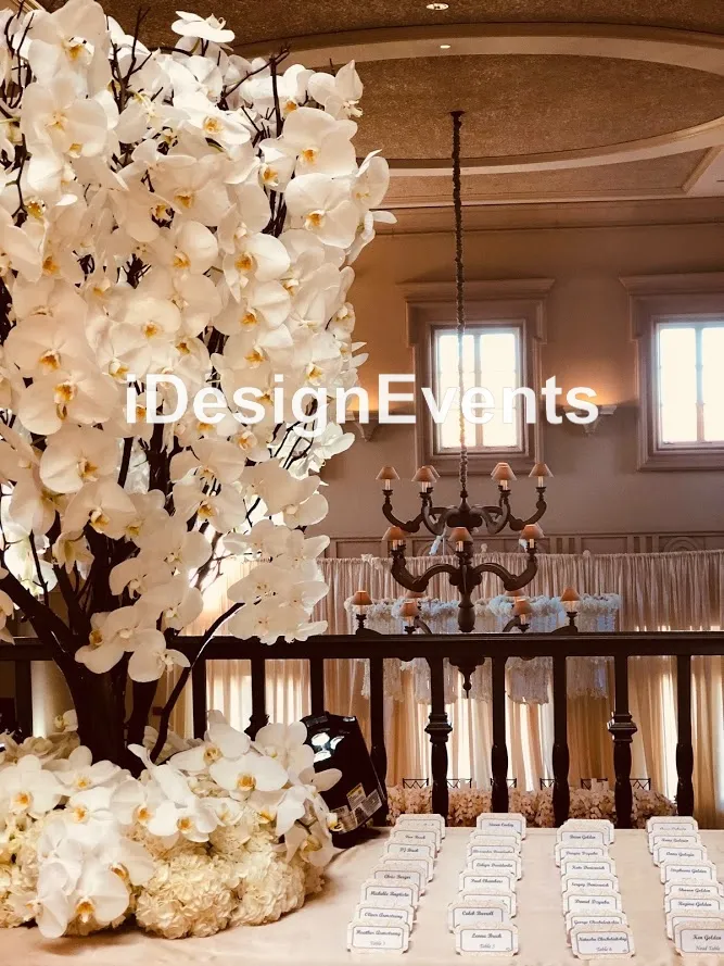 Elegant floral decor with white blossoms and chandeliers in a sophisticated event space.
