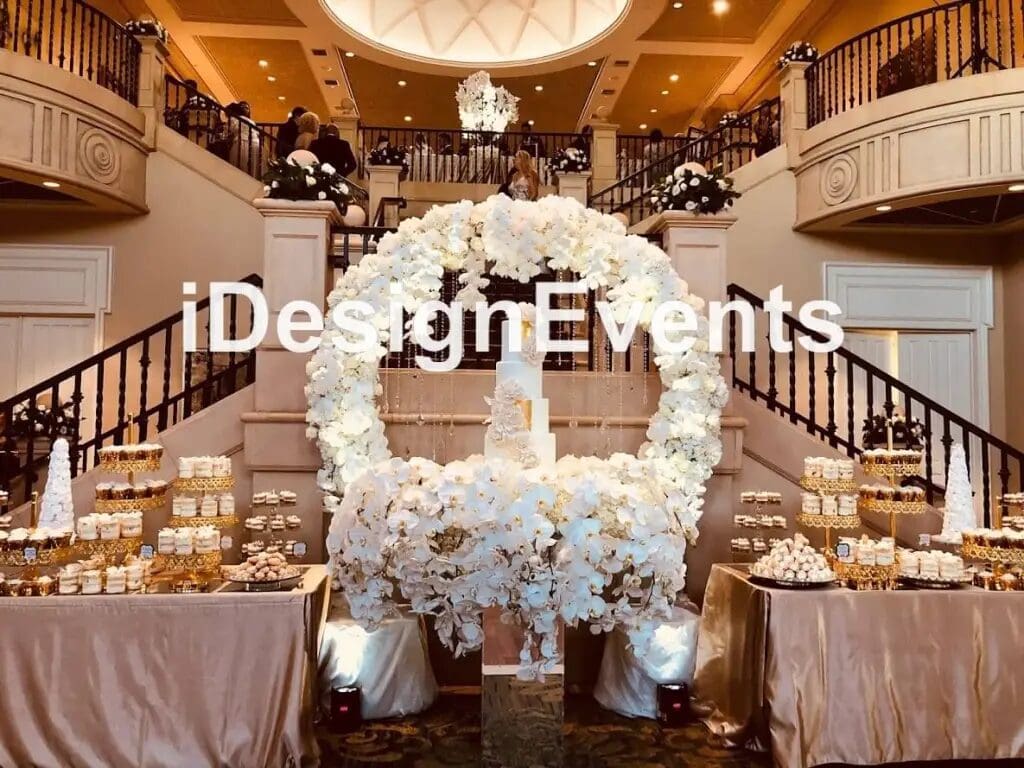 Elegant white floral wedding arch in a grand ballroom.