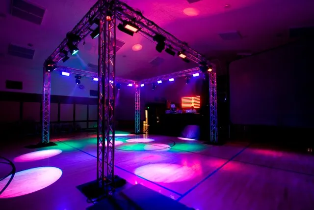 Futuristic roller coaster inside a vibrant, neon-lit indoor amusement park.