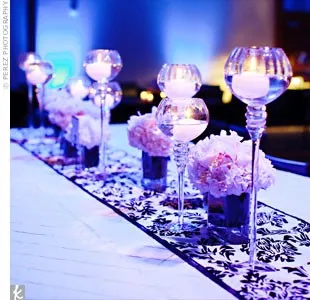 Elegant table centerpiece with glass candle holders and purple flowers.
