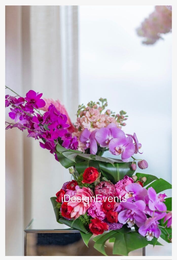 A vibrant bouquet of pink and purple orchids with green leaves.