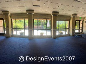 Empty event hall with large windows and blue carpet.