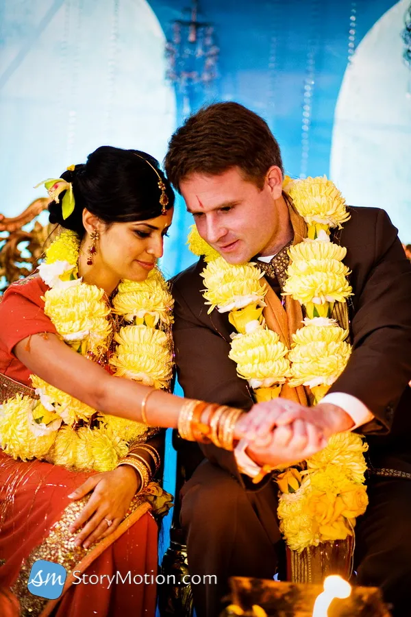 A couple dressed in traditional attire, exchanging rings during a wedding ceremony.